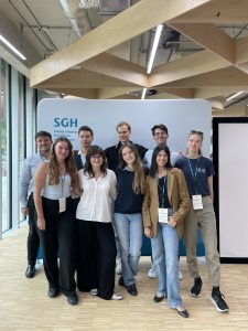 Nine student ambassadors smiling in front of an SGH—Szkoła Główna Handlowa backdrop inside a bright, modern hall