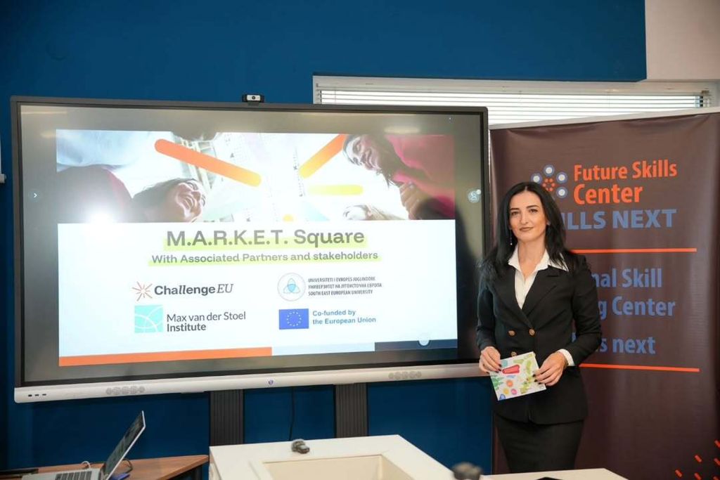 A speaker stands beside a large display reading “M.A.R.K.E.T. Square,” with ChallengeEU and EU co-funded logos at the Future Skills Center.