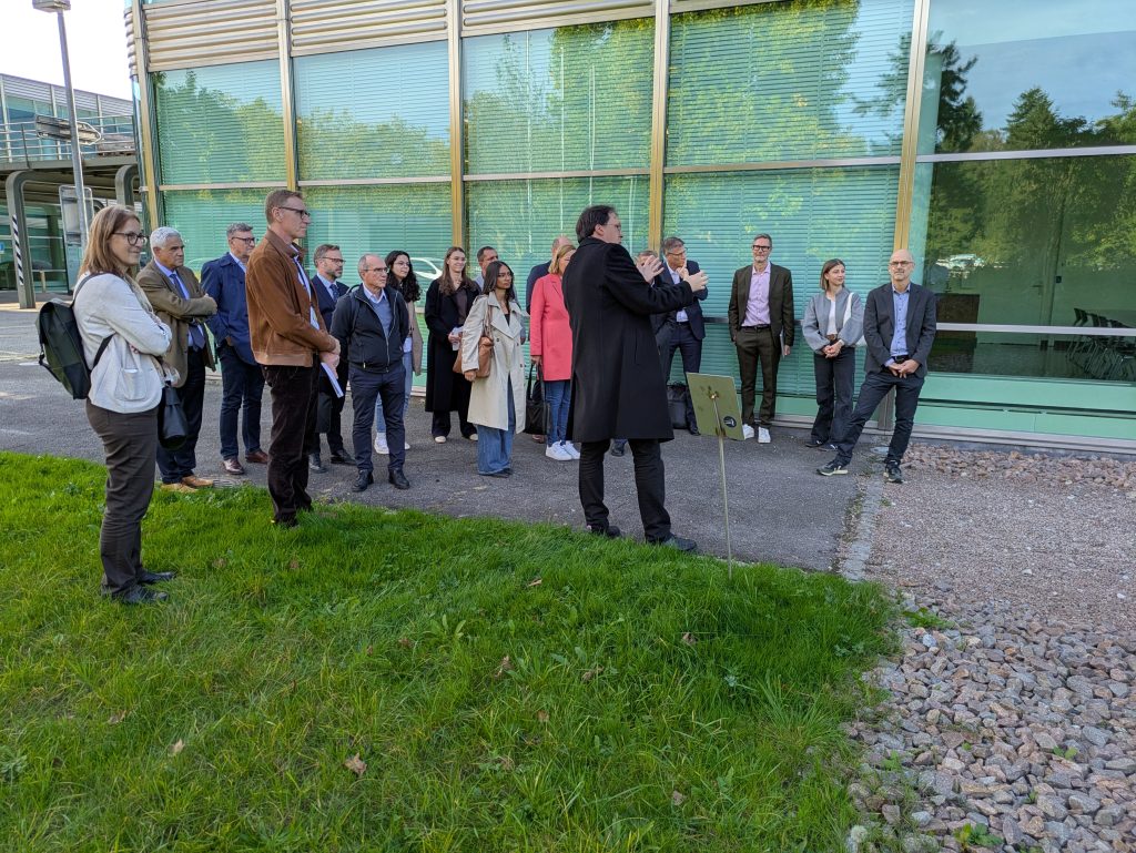 Group of delegates standing outside a glass-fronted FHNW building during a campus tour