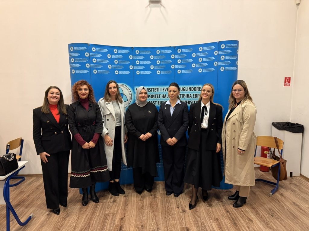 Group photo of seven women standing in front of a blue SEEU Faculty of Law backdrop during the “Orange for Awareness” seminar.
