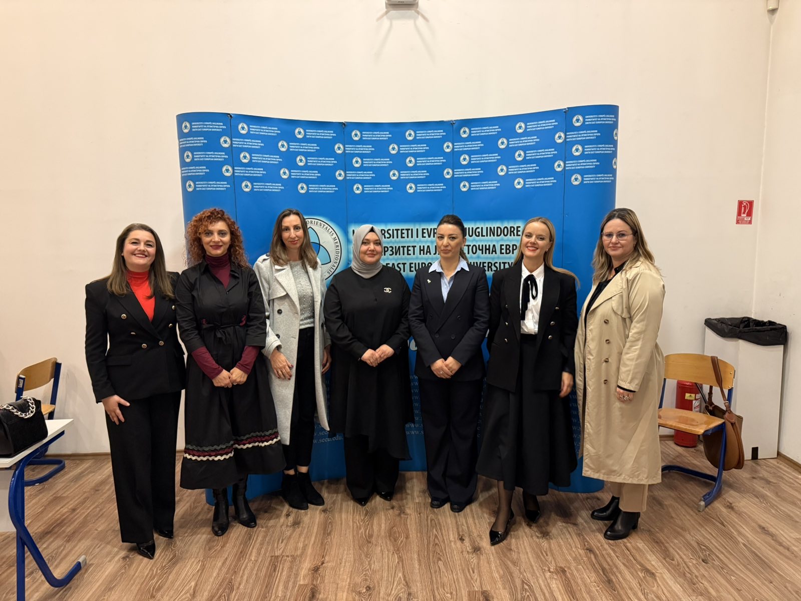 Group photo of seven women standing in front of a blue SEEU Faculty of Law backdrop during the “Orange for Awareness” seminar.