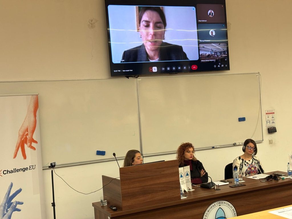 Hybrid presentation during the seminar, with an online speaker shown on the screen above the panel desk.