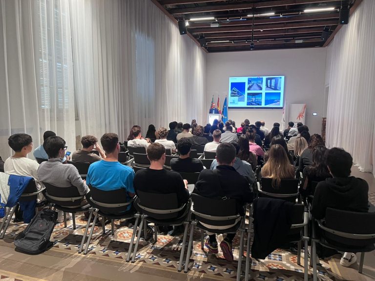 Students seated in a bright auditorium during Talent Day at Universidad Europea de Valencia, listening to a speaker presenting slides on a large screen at the front of the room