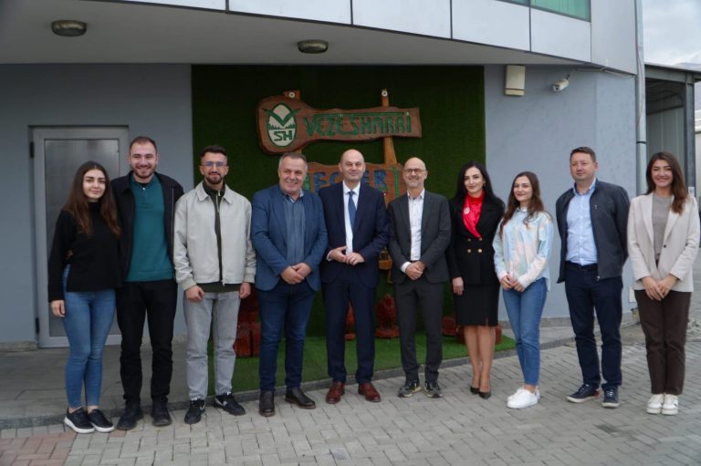 Group photo of representatives from Hochschule Offenburg, South East European University and Veze Sharri standing in front of the Veze Sharri company building and logo