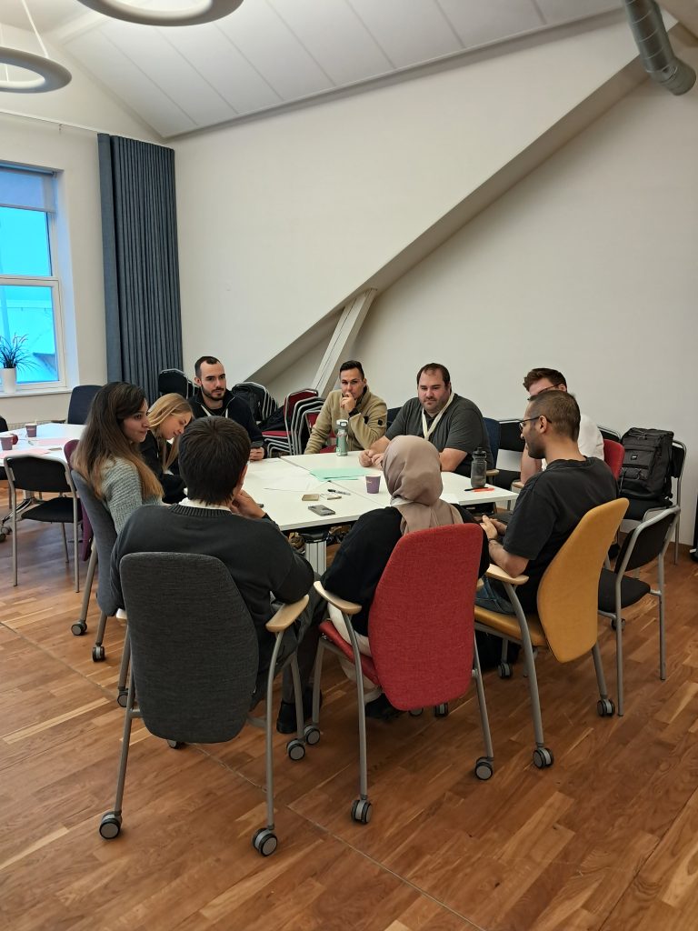 Small-group discussion during the workshop, with participants seated around a table and working on notes and materials.