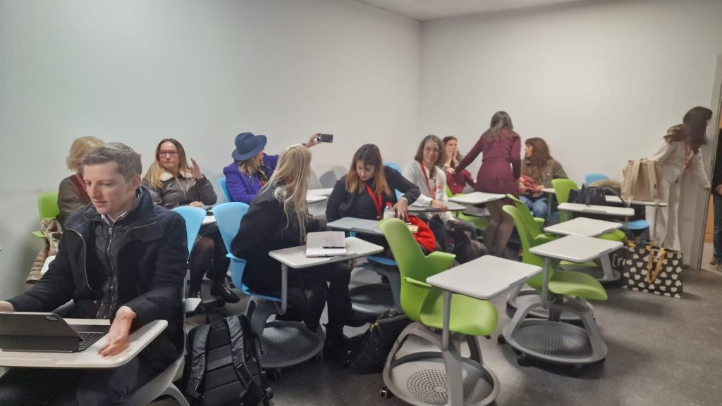 Participants gather informally in a seminar room, preparing for the next workshop session and continuing discussions.