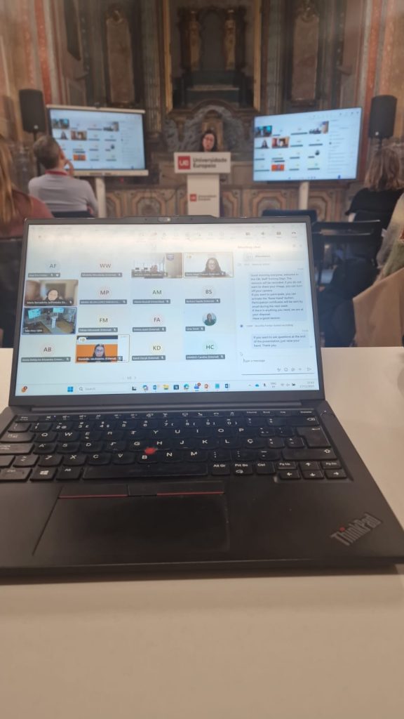 Hybrid learning setup showing an online meeting displayed on a laptop screen during an in-person academic event.