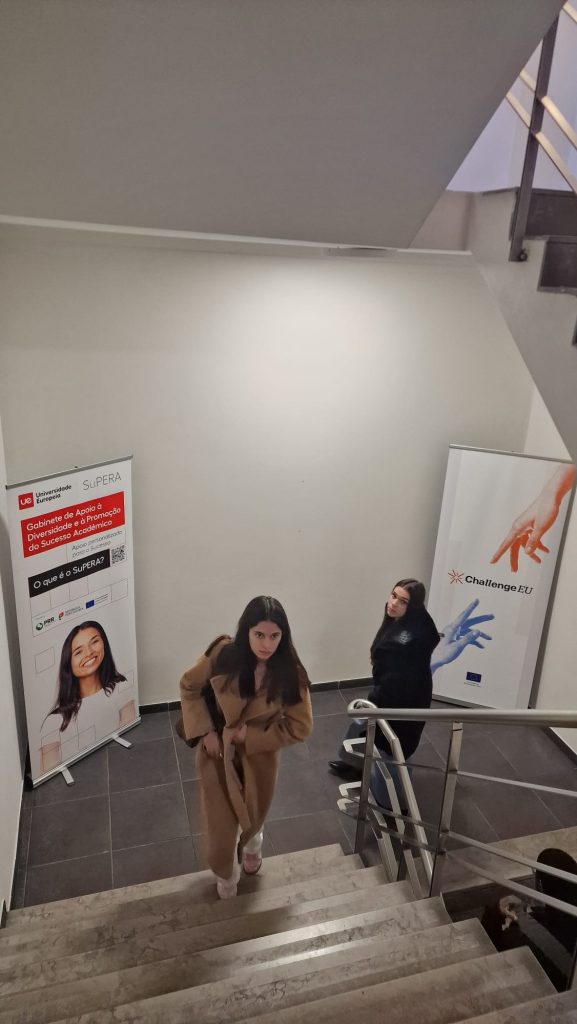 Participants walk up a staircase inside a university building, with ChallengeEU and institutional banners displayed in the background.