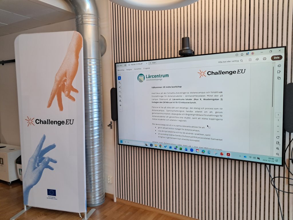 A ChallengeEU roll-up banner stands next to a large wall-mounted screen displaying a workshop agenda in Swedish, including the logos of Lärcentrum and ChallengeEU. The room features wooden flooring and light-coloured walls with vertical paneling.