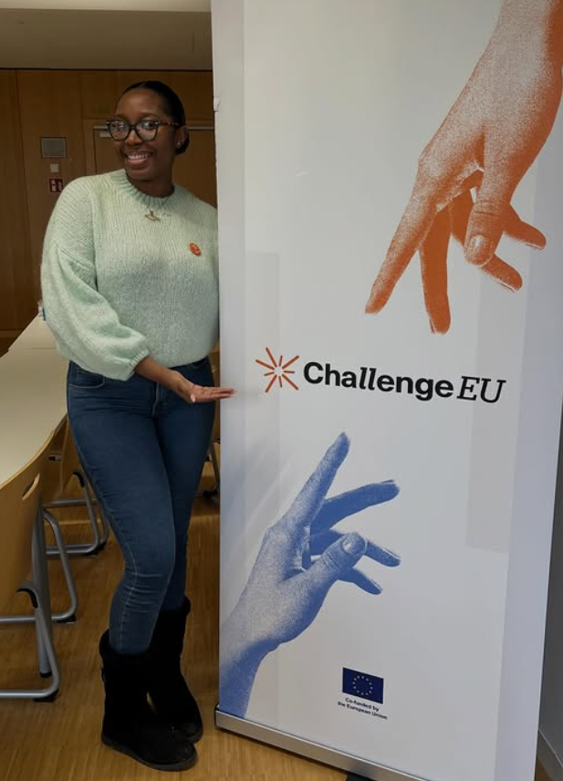 Georden, student ambassador, stands next to a banner with the ChallengeEU logo.