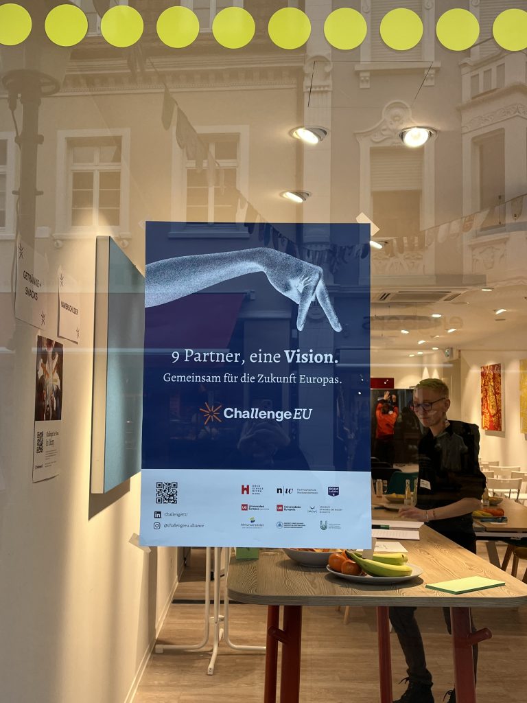 ChallengeEU poster displayed in the Stadtraum Offenburg window reading “9 Partner, eine Vision. Gemeinsam für die Zukunft Europas,” with workshop participants visible inside.