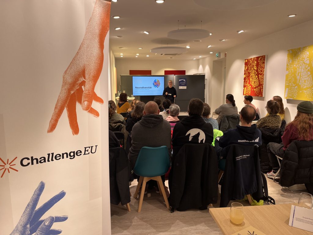 Audience seated at a ChallengeEU neurodiversity workshop in Stadtraum Offenburg, with a speaker presenting at the front and a ChallengeEU banner visible in the foreground.