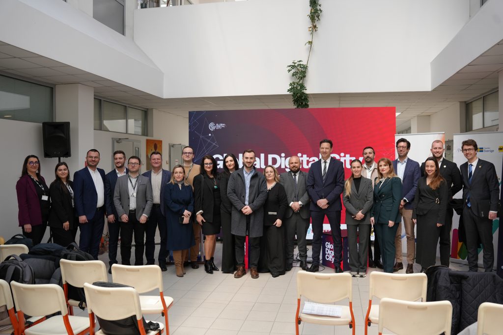Group photo of event organisers and partners standing on stage in front of a Global Digital City backdrop.