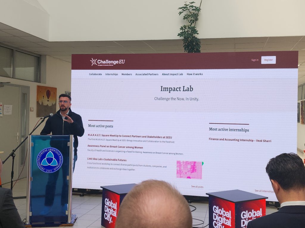 Presenter introducing the ChallengeEU Impact Lab platform, with the project website displayed on a large screen behind him.