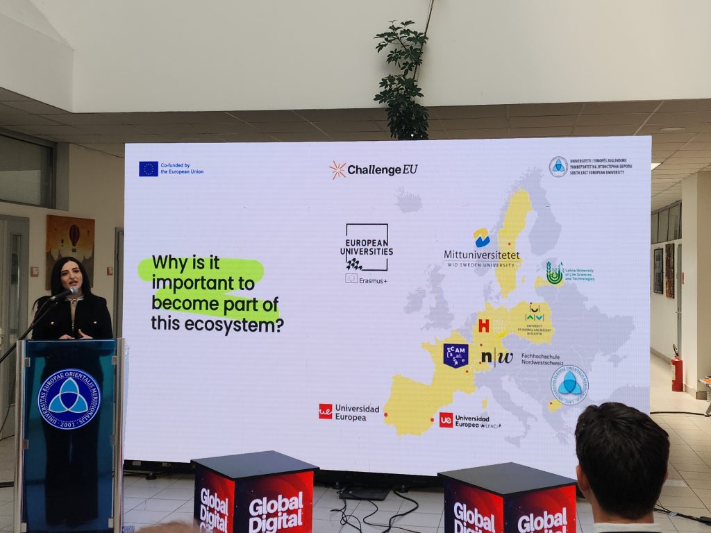 Speaker presenting ChallengeEU on stage, with a slide showing a map of Europe and the question “Why is it important to become part of this ecosystem?”.