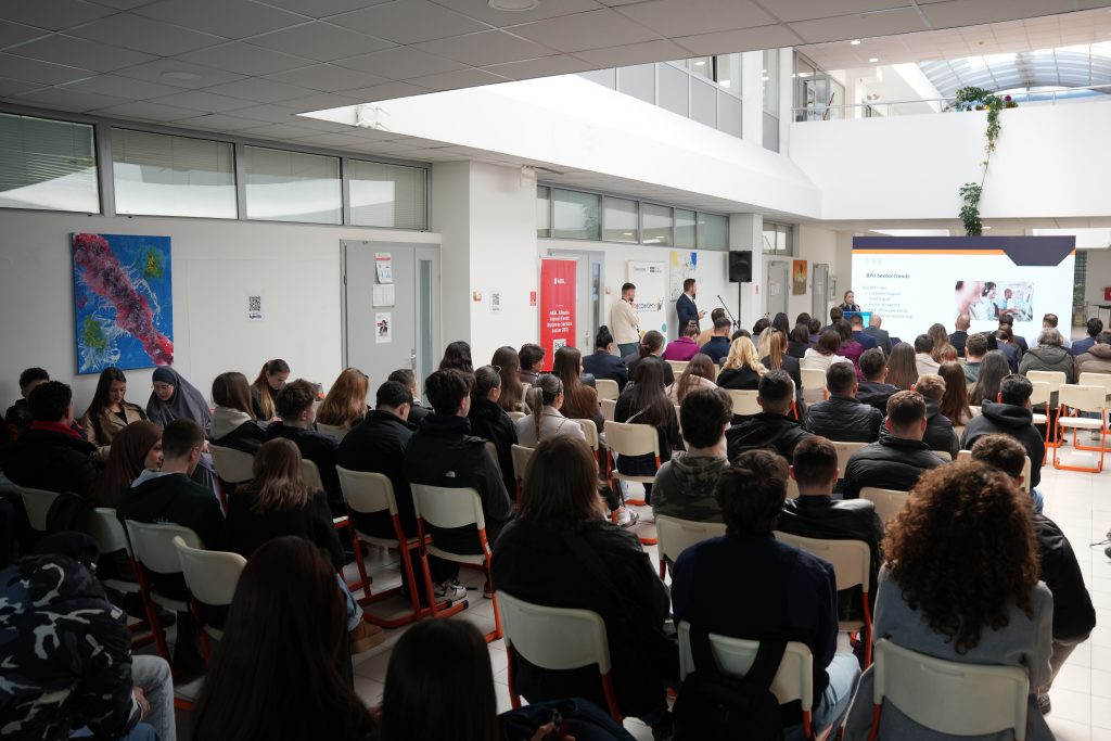Audience seated in a university hall attending the Global Digital City event, facing a large presentation screen.