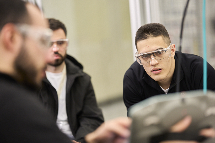 Students wearing safety goggles watch a practical demonstration in the robotics lab during the Blended Intensive Programme.