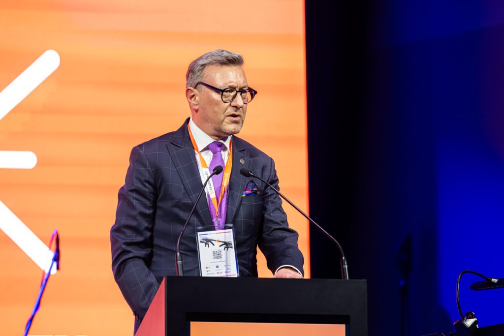 A speaker stands at the podium during the ChallengeEU 1st Annual Conference opening session, with a large ChallengeEU screen behind hum.