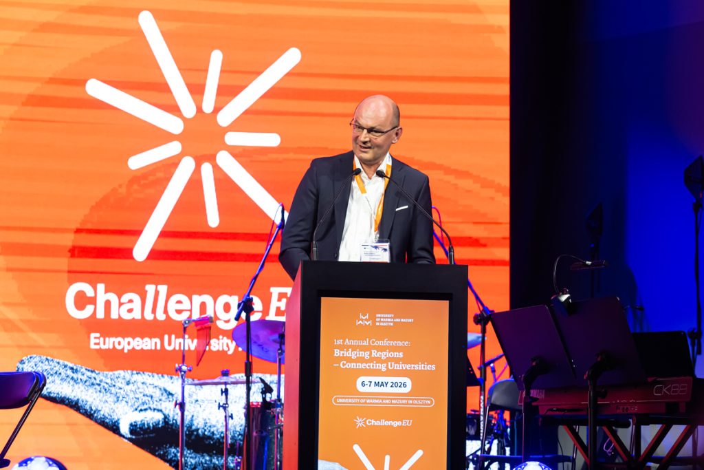 A speaker stands at the podium during the ChallengeEU 1st Annual Conference opening session, with a large ChallengeEU screen behind him.