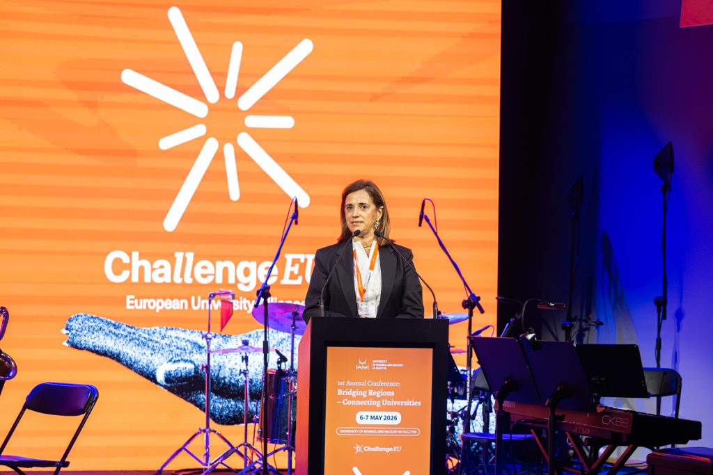 A speaker stands at the podium during the ChallengeEU 1st Annual Conference opening session, with a large ChallengeEU screen behind her.