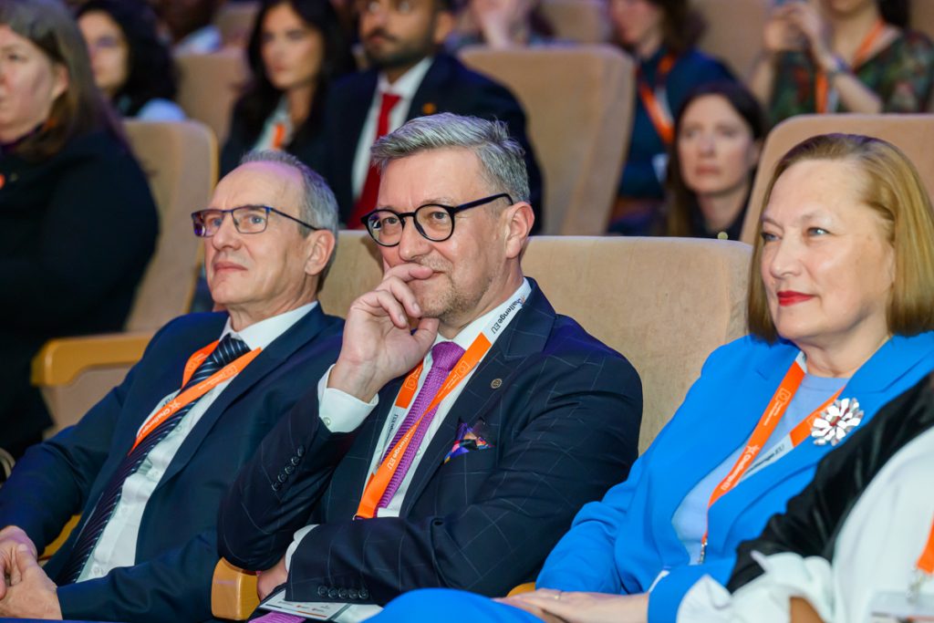 Conference guests wearing ChallengeEU lanyards sit in the auditorium and listen during the opening session.