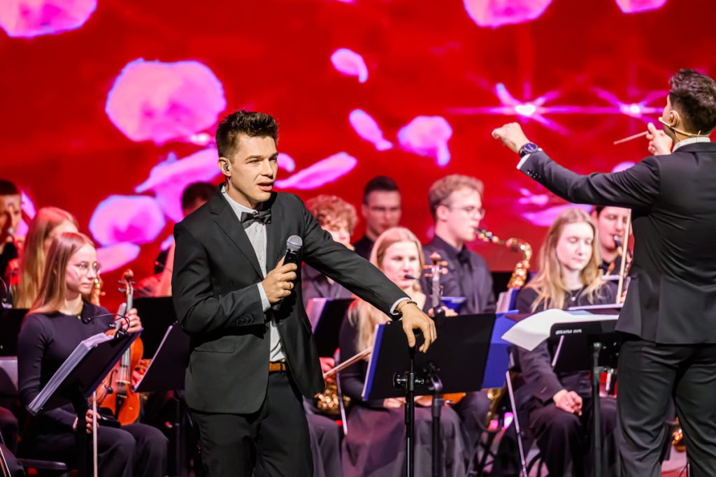 A vocalist and orchestra perform on stage during the artistic part of the ChallengeEU 1st Annual Conference.