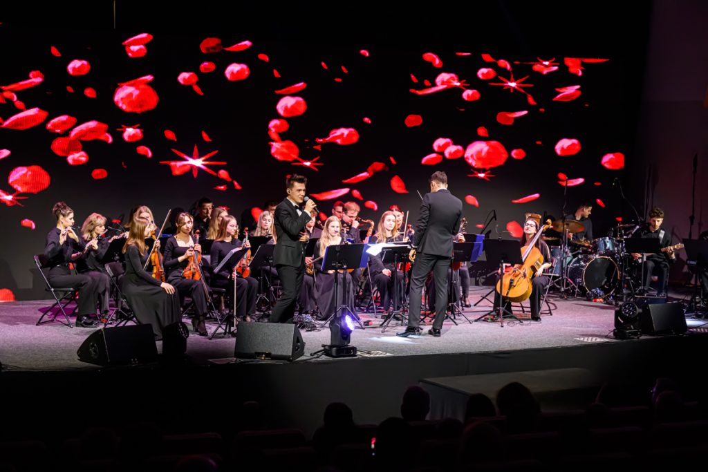 A vocalist and orchestra perform on stage during the artistic part of the ChallengeEU 1st Annual Conference.