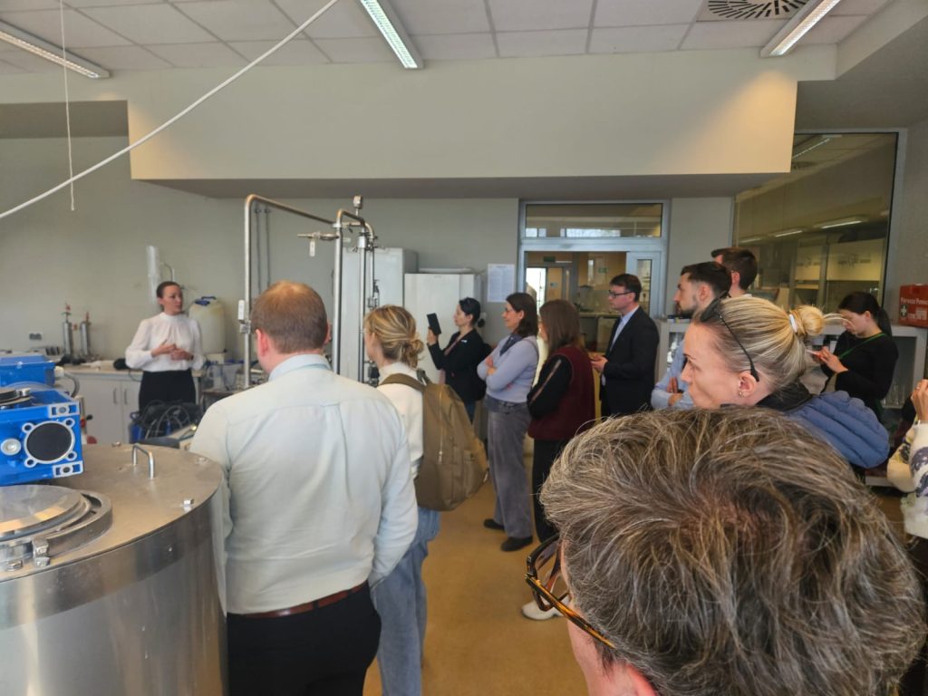 Participants gathered in a laboratory at the University of Warmia and Mazury, listening to a guide explaining environmental engineering equipment used for water treatment and research.