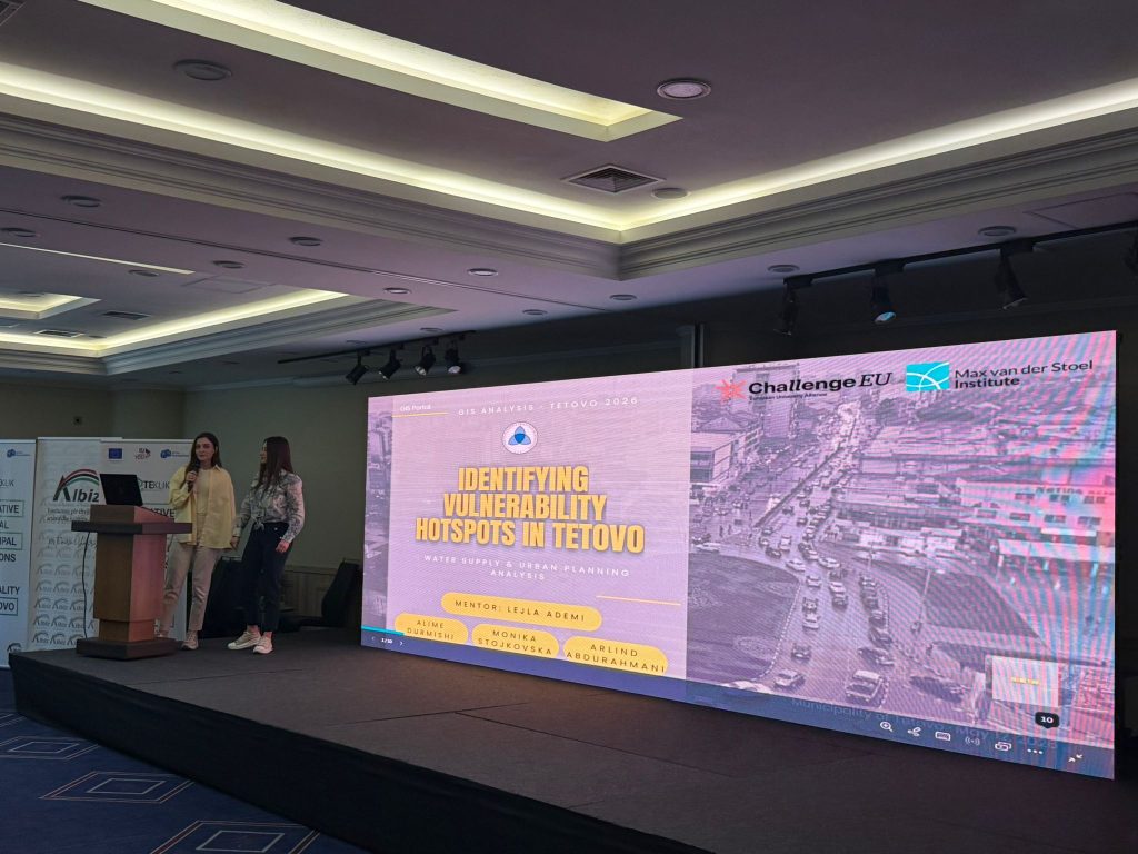 A student presents the GIS project “Identifying Vulnerability Hotspots in Tetovo” on stage, with the ChallengeEU and Max van der Stoel Institute logos displayed on the screen.