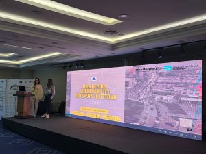 A student presents the GIS project “Identifying Vulnerability Hotspots in Tetovo” on stage, with the ChallengeEU and Max van der Stoel Institute logos displayed on the screen.