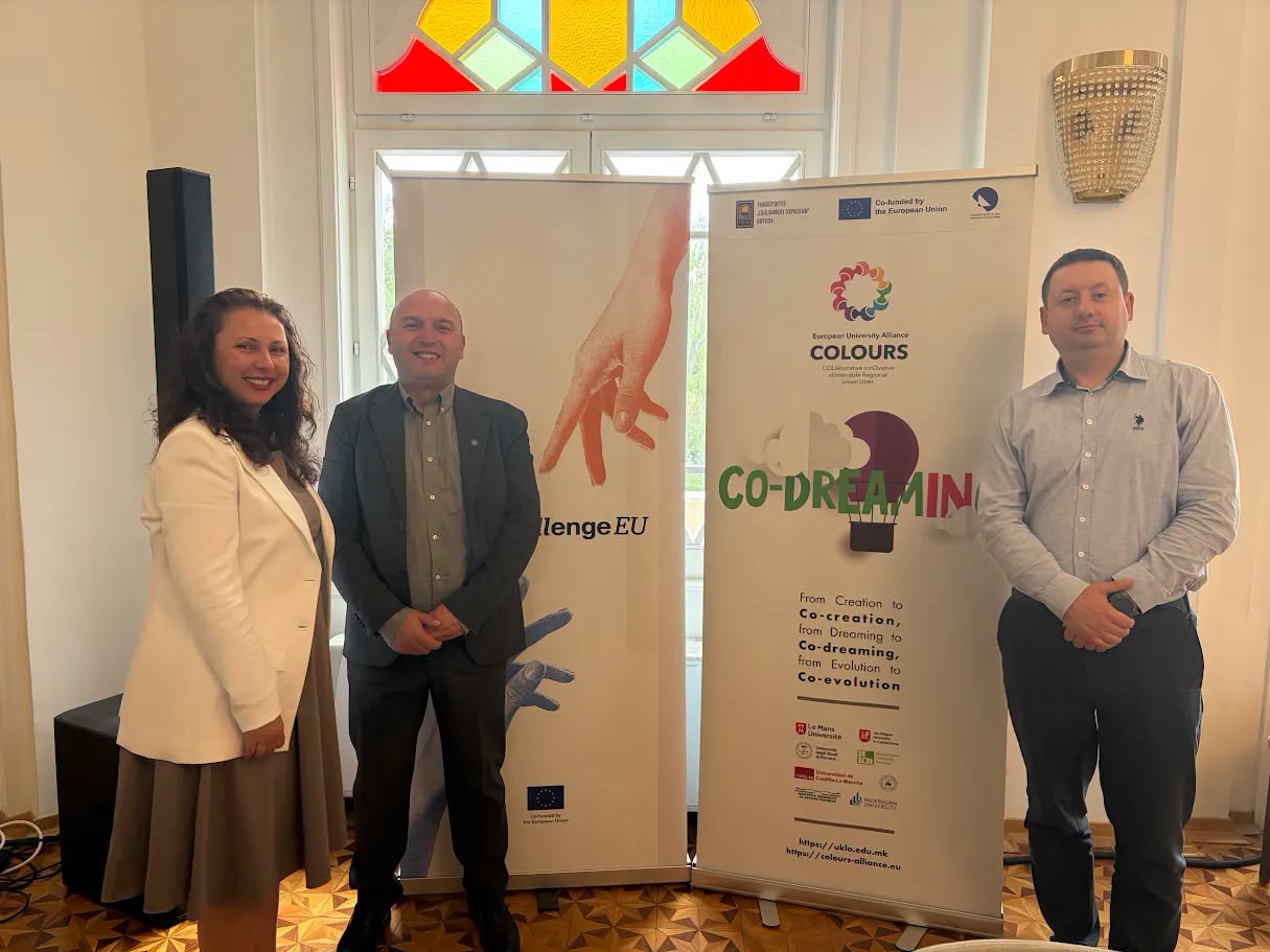 Three people stand next to the ChallengeEU and Colours roll-ups