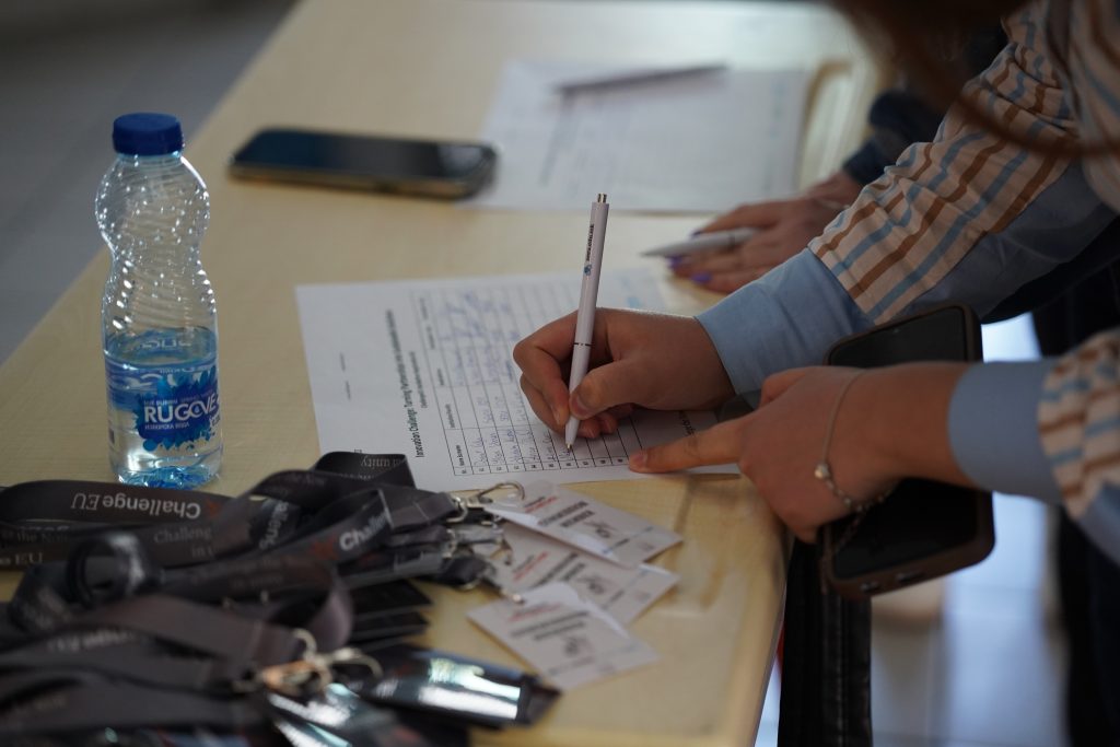 Close-up of an attendance list, ChallengeEU badges and a participant signing in for the event.