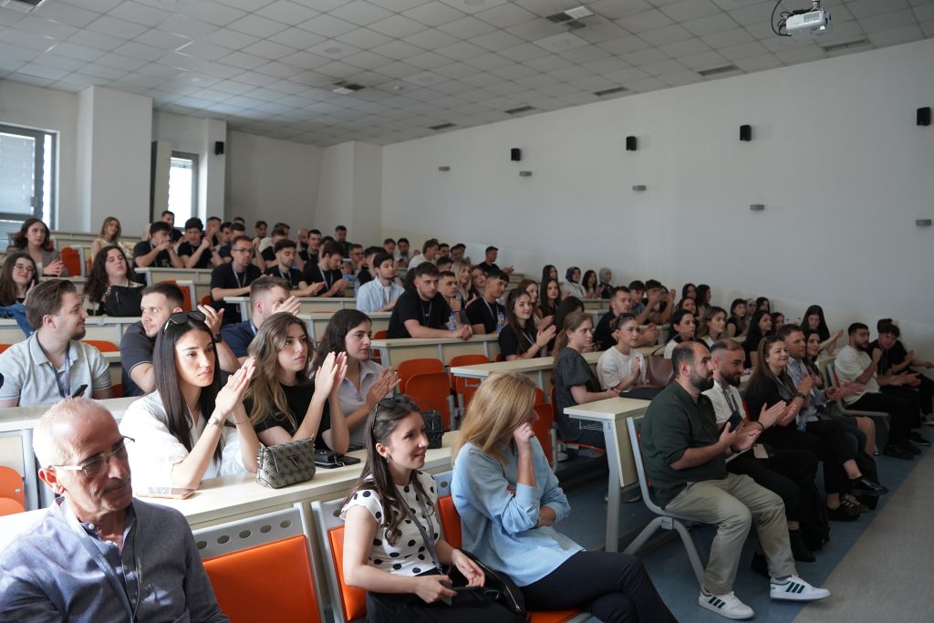 Hackathon participants sit in a lecture hall and listen to a presentation.