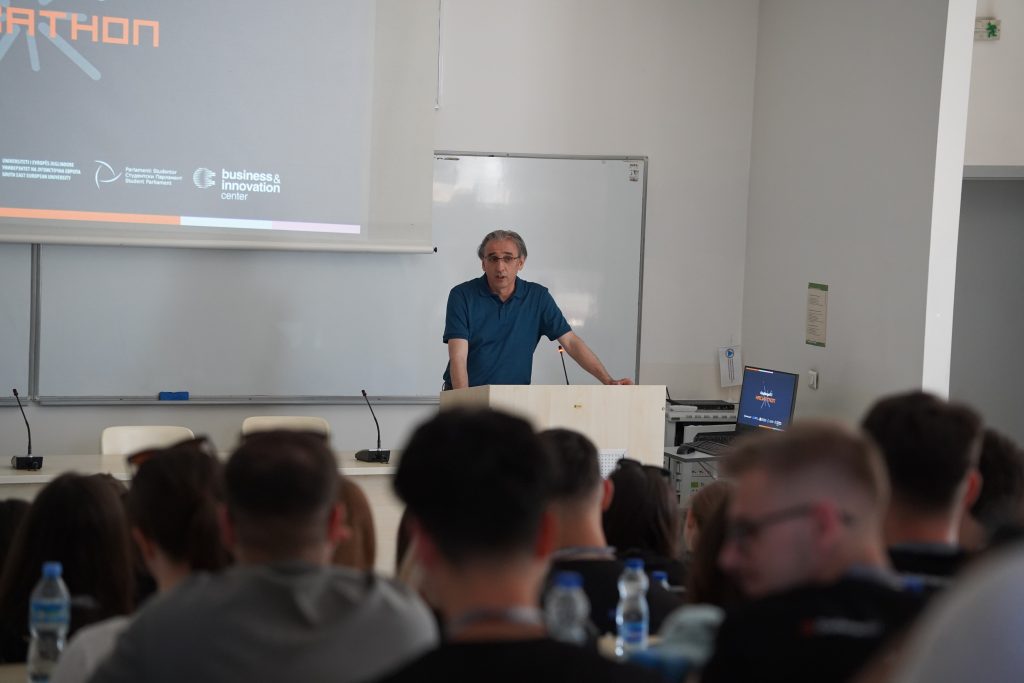 A speaker gives a presentation to hackathon participants in a lecture hall.