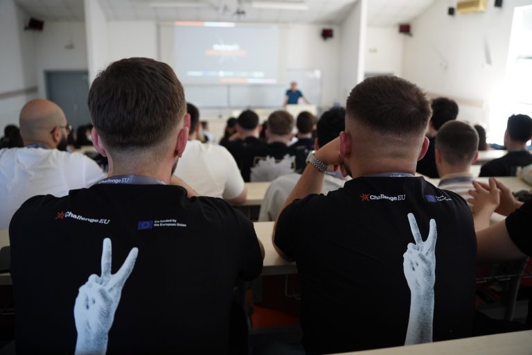 Hackathon participants sit in a lecture hall during the opening presentation of the ChallengeEU event.