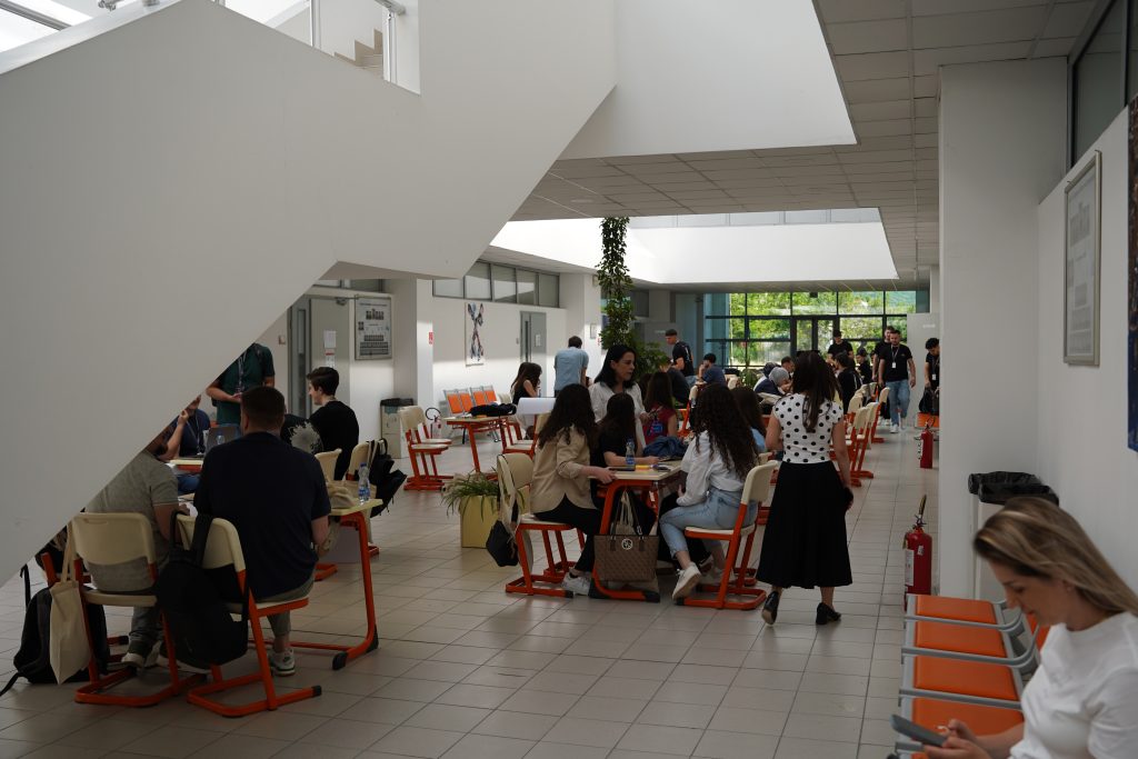 Hackathon participants work in groups at tables in a bright hall on the SEEU campus in Tetovo.