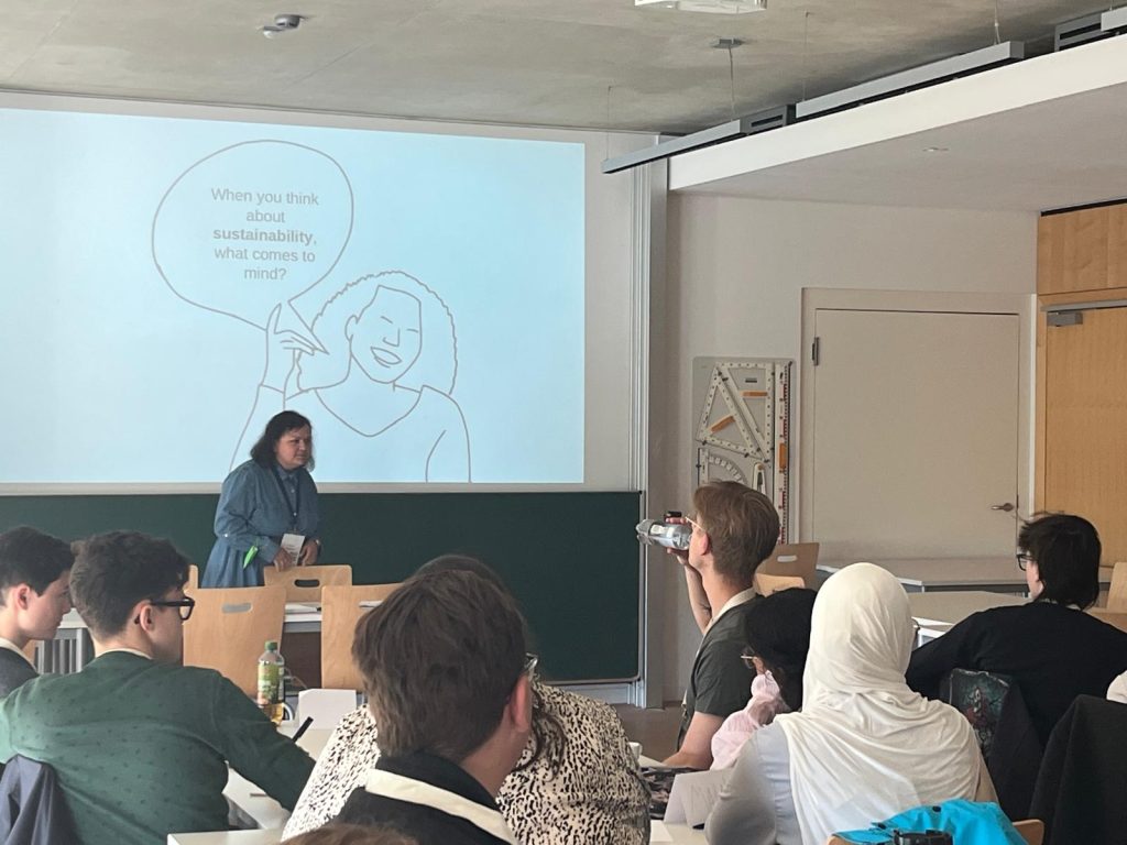 A lecturer gives a presentation on sustainability to students in a classroom.