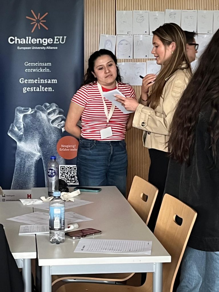 A student presents notes to a small group next to a ChallengeEU banner.