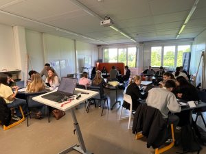 Students take part in a workshop session in a classroom, with a presentation displayed on the screen.