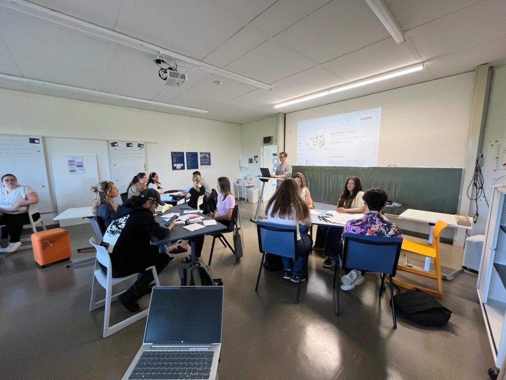Students take part in a workshop session in a classroom, with a presentation displayed on the screen.