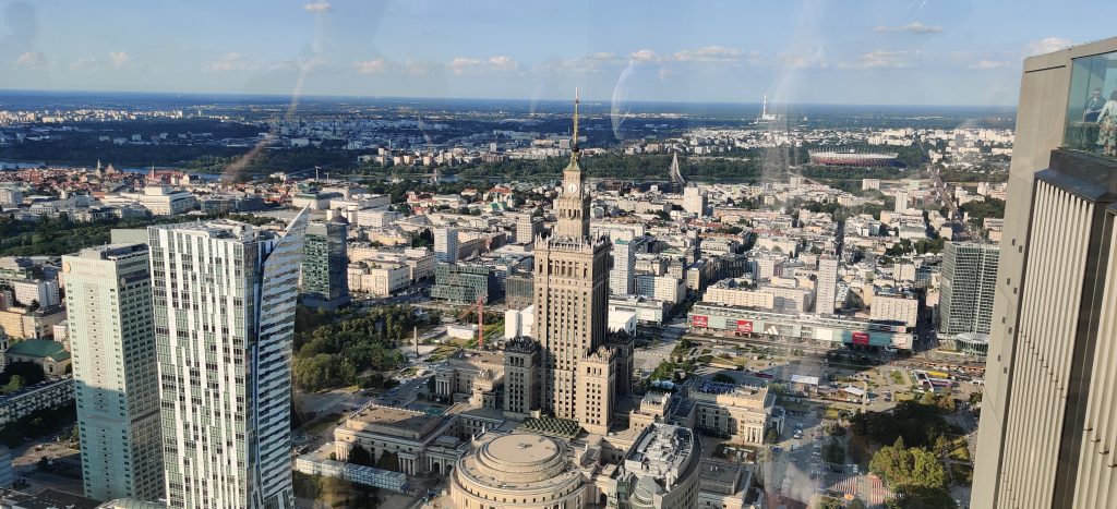 Panoramic view of Warsaw city centre from a high observation deck, with the Palace of Culture and Science in the foreground.