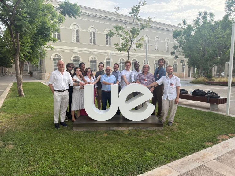 Participants standing together around the Universidad Europea logo in a green courtyard on the Valencia campus.