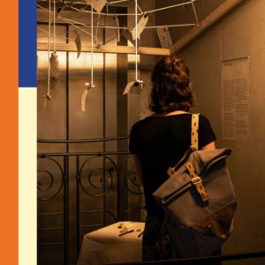 A visitor views an art installation featuring suspended strings, handwritten notes and objects at the Werkschau exhibition at Hochschule Offenburg.